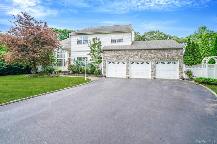 Traditional-style home featuring asphalt driveway, stone siding, and a garage