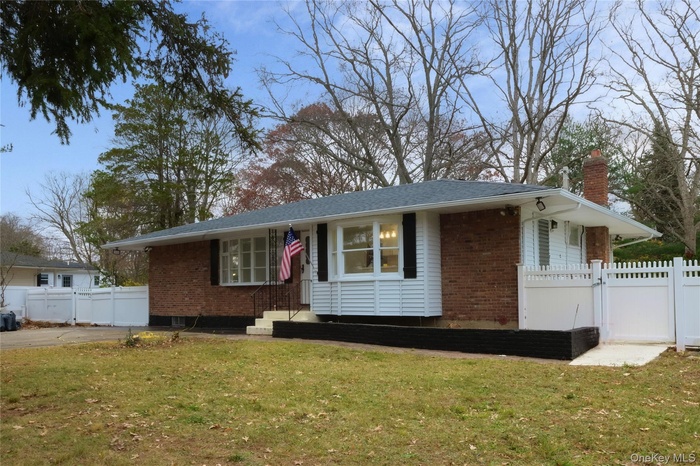 Single story home featuring brick siding, a chimney, and a gate