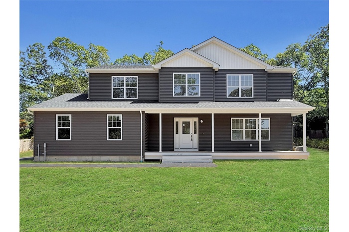 View of front of house featuring a porch, a shingled roof, a front yard, and board and batten siding