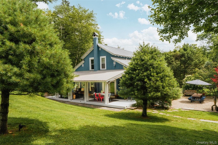 Rear view of house with covered patio and landscaped dining area to the side