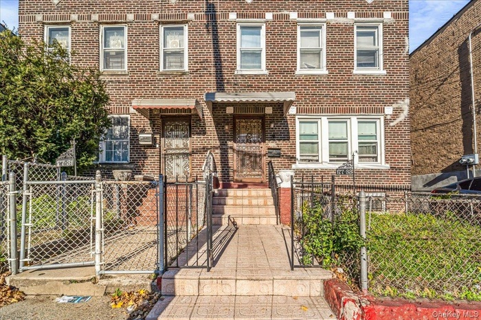 View of front of home featuring a gate, brick siding, and a fenced front yard