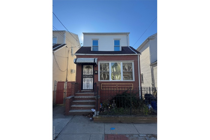 View of front of home featuring a fenced front yard, brick siding, roof with shingles, and a gate