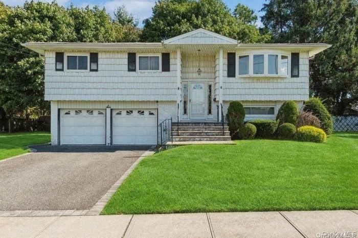 Split foyer home with driveway, a front yard, and a garage