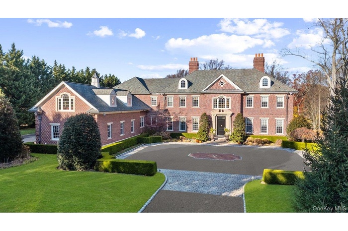 View of front facade featuring a chimney, brick siding, a front yard, and driveway