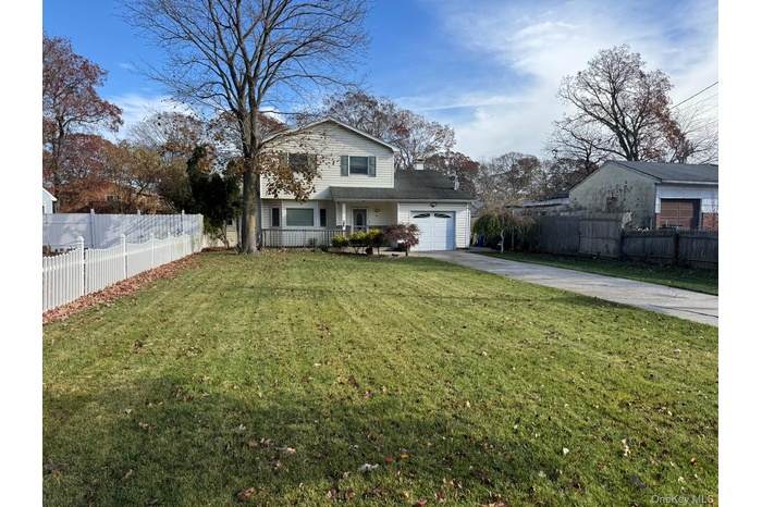 Traditional-style house with driveway, covered porch, and an attached garage