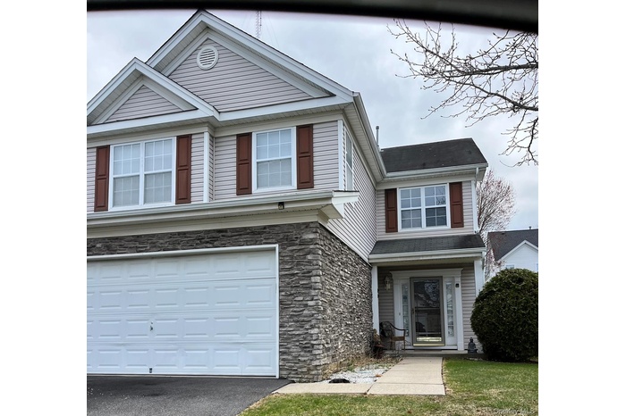 View of front of property featuring stone siding, driveway, and an attached garage
