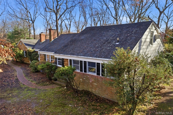 View of side of home featuring a sunroom, a chimney, and brick siding