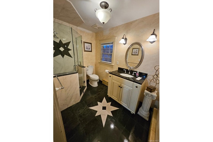 Bathroom with vanity, a stall shower, and a baseboard radiator