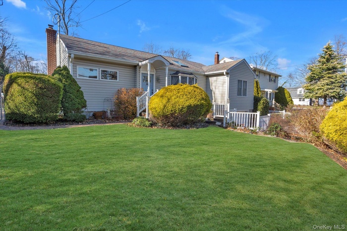 View of front of house featuring a chimney and a front lawn