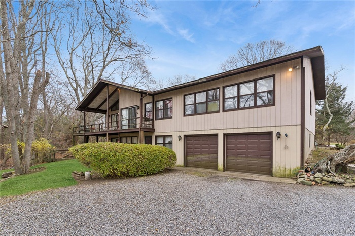 Mid-century inspired home featuring driveway, an attached garage, and a balcony