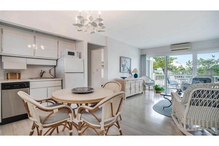 Dining room with a chandelier, light wood-style floors, and a wall mounted AC