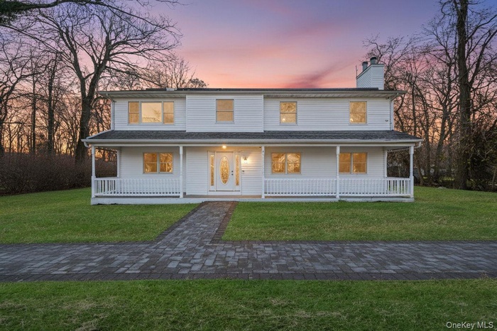 View of front of home featuring a porch, a chimney, and a yard
