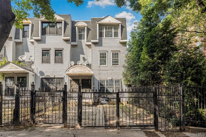 View of front of house featuring a shingled roof, mansard roof, a gate, and a fenced front yard