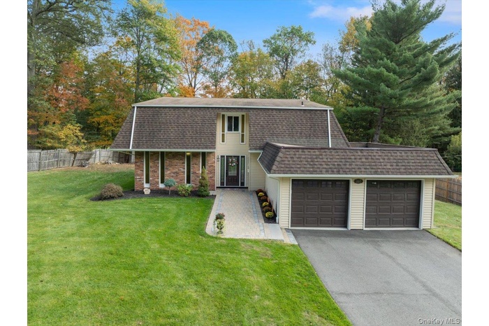 Colonial inspired home featuring roof with shingles, a garage, driveway, and a gambrel roof
