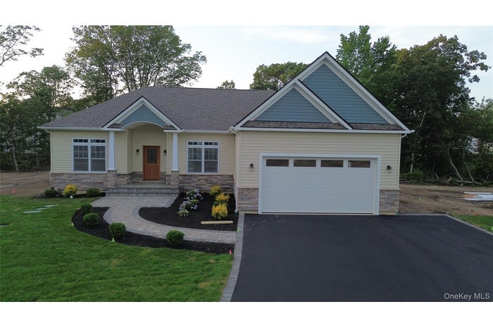 Craftsman house with asphalt driveway, stone siding, a front lawn, a shingled roof, and a garage