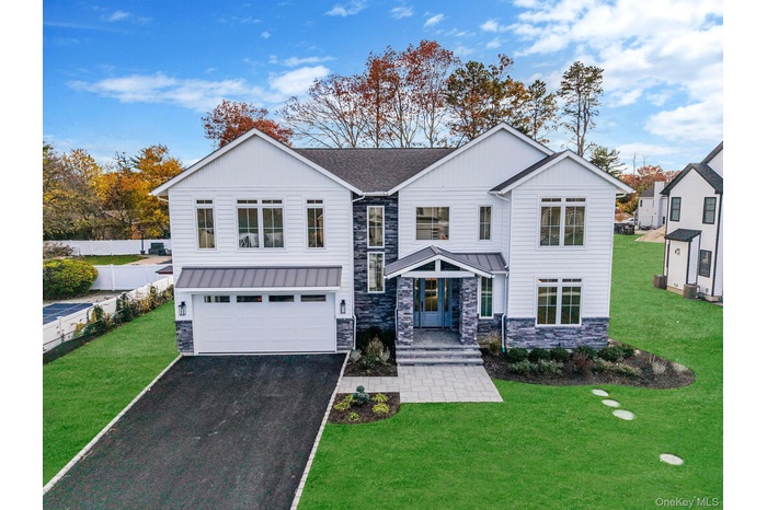 Modern inspired farmhouse with stone siding, driveway, a garage, and a standing seam roof
