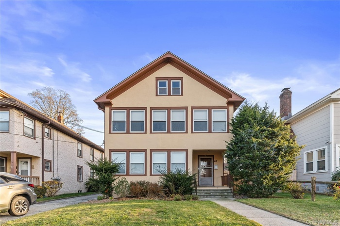 View of front of home featuring stucco siding and a front yard