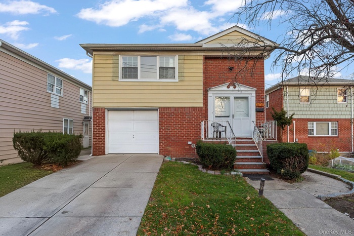 View of front facade with brick siding, driveway, an attached garage, and a front lawn