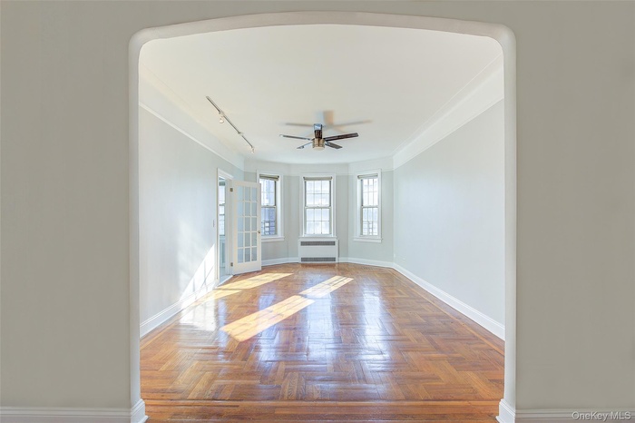 Spare room with track lighting, ceiling fan, and arched walkways