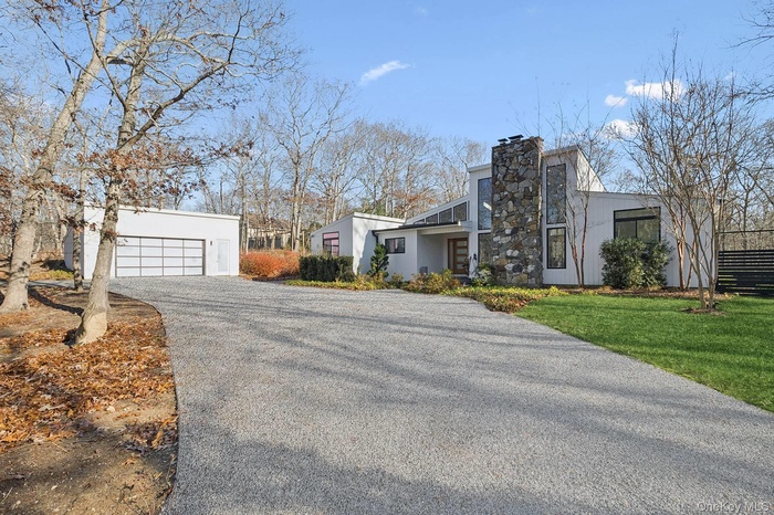 View of front of home featuring an outdoor structure, stucco siding, driveway, and a chimney