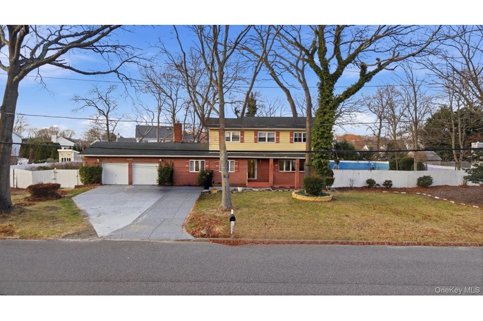 Traditional-style home featuring concrete driveway, a porch, brick siding, a garage, and a chimney