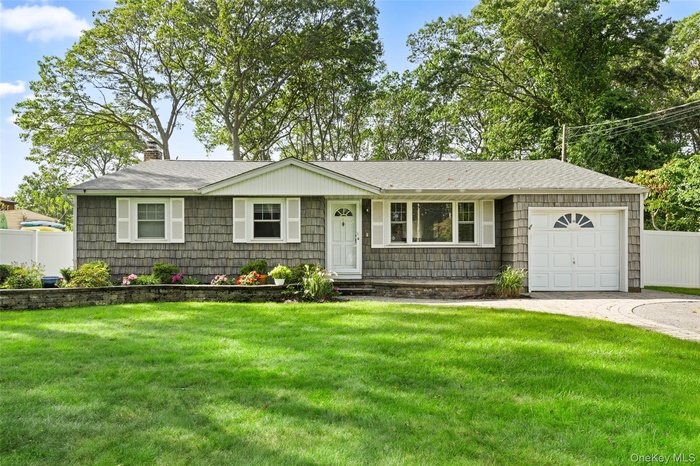 Single story home featuring a chimney, a shingled roof, an attached garage, and driveway