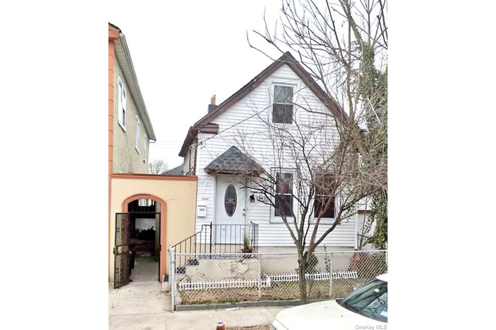 View of front of home with a fenced front yard, a chimney, and a gate