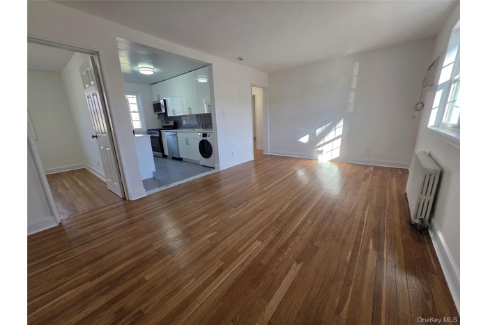 Unfurnished living room with radiator, dark wood-type flooring, and washer / dryer
