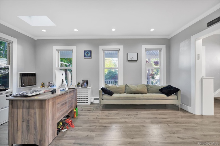 Office space featuring light wood-style floors, crown molding, recessed lighting, a skylight, and baseboard heating