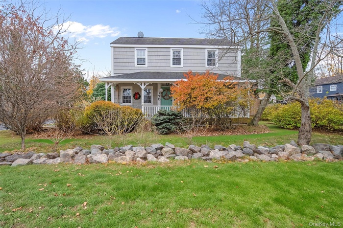 View of front of home with a front yard, a porch, and a shingled roof