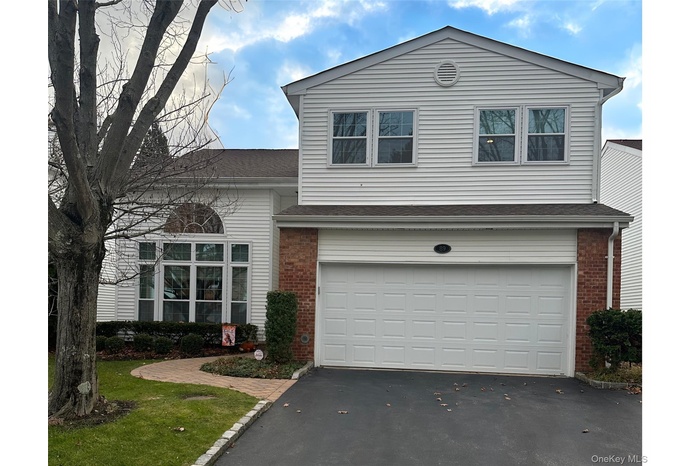 View of front of home with brick siding, asphalt driveway, roof with shingles, and an attached garage
