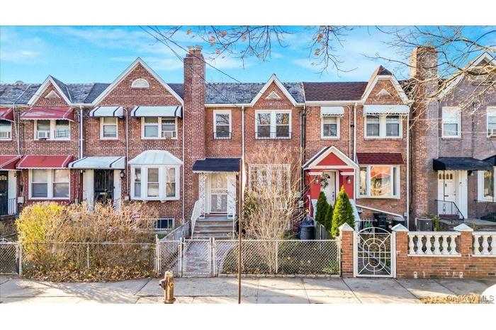 Traditional-style house featuring a gate, a fenced front yard, brick siding, and a residential view