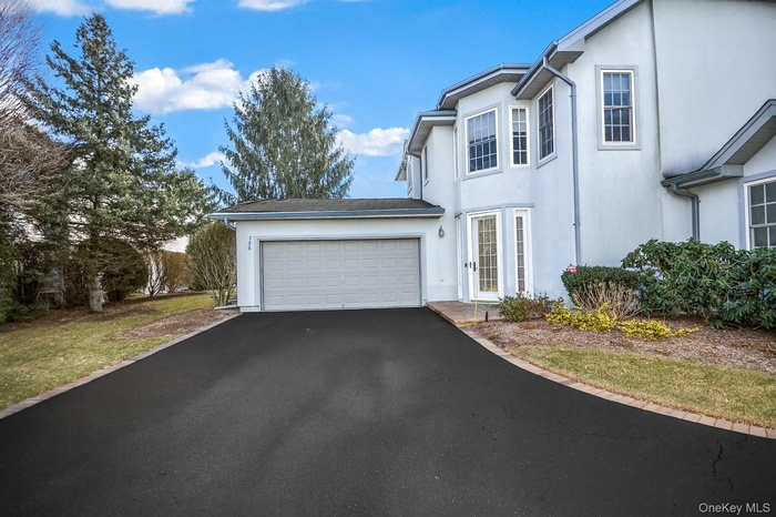 Traditional-style house with stucco siding, driveway, and a garage