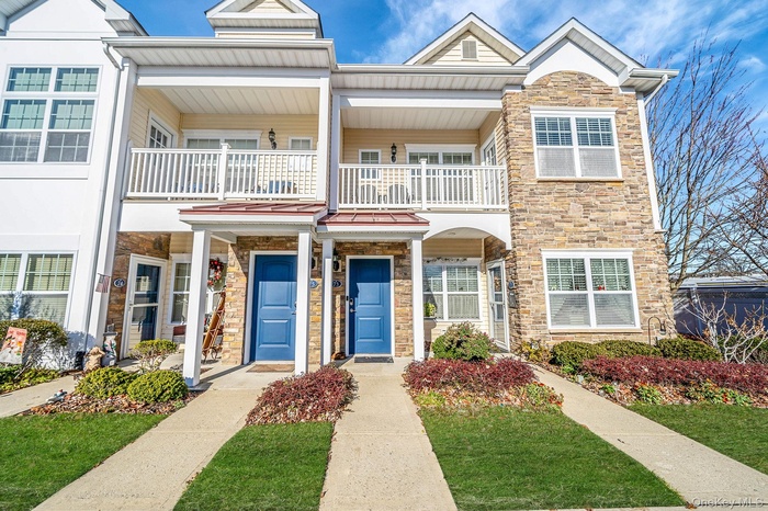 Traditional-style home featuring stone siding, a balcony, covered porch, and a front lawn