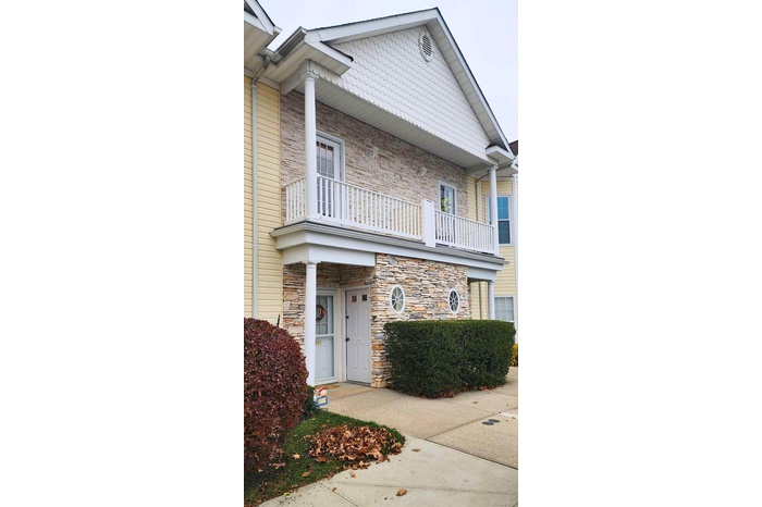 View of front facade with a balcony and stone siding