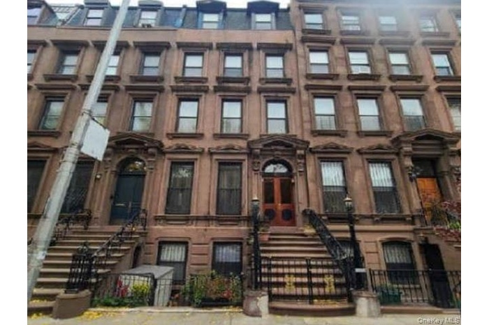 View of building exterior featuring a fenced front yard and stairway