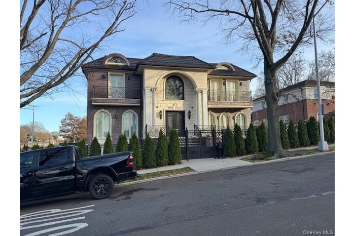 View of front facade with a balcony, a gate, a fenced front yard, and french doors