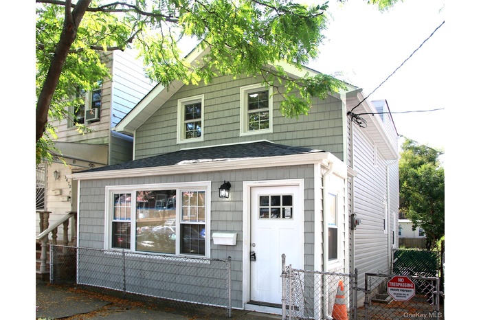 View of front of home featuring roof with shingles and a gate