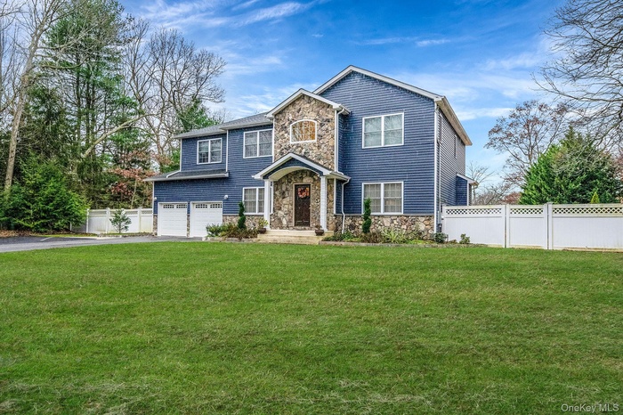 View of front of house featuring stone siding, a garage, and asphalt driveway