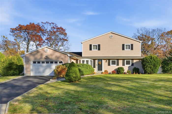 View of front facade featuring a front yard, driveway, and an attached garage