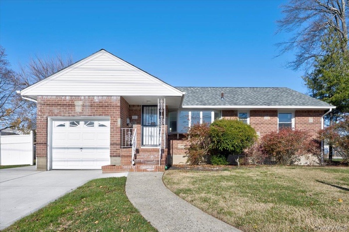 View of front of house featuring a front yard, brick siding, an attached garage, driveway, and a shingled roof