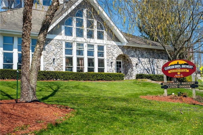 Rear view of property featuring stone siding and a yard