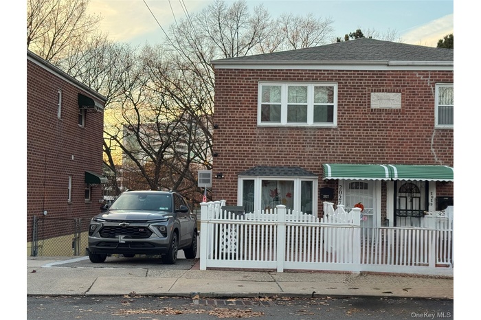 Traditional-style home featuring a fenced front yard, brick siding, and roof with shingles