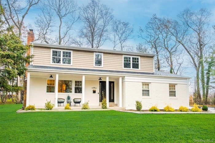 View of front facade featuring a porch, a front yard, and a chimney