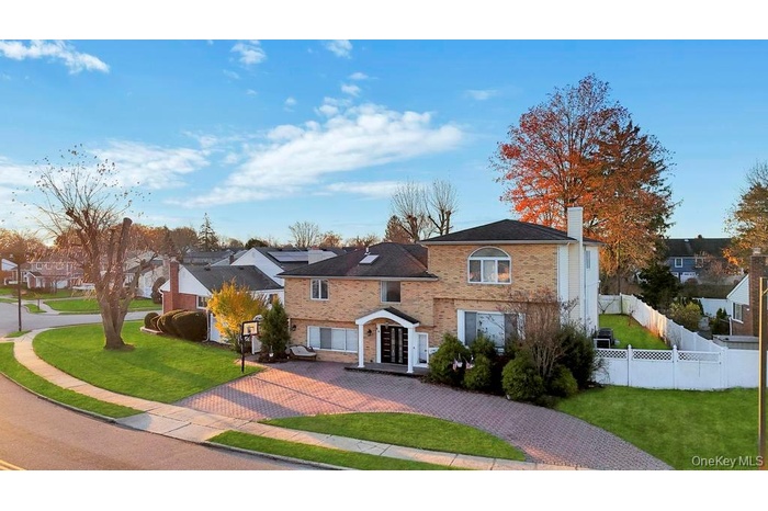 View of front of house featuring a chimney, brick siding, decorative driveway, and a residential view