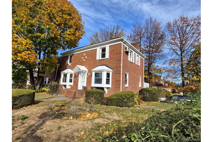 Colonial house featuring a chimney and brick siding