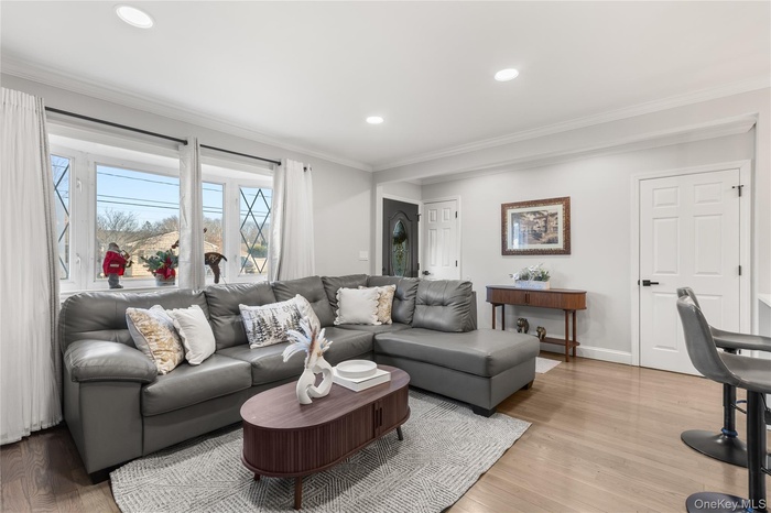 Living area featuring light wood-style flooring, crown molding, and recessed lighting