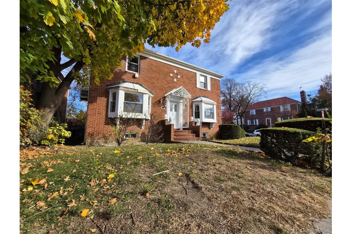 Colonial inspired home with brick siding and a front lawn