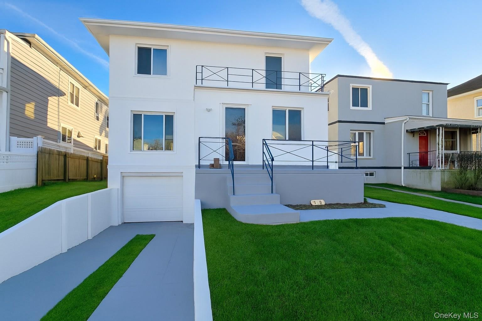 Rear view of property with stucco siding, a yard, driveway, and a garage