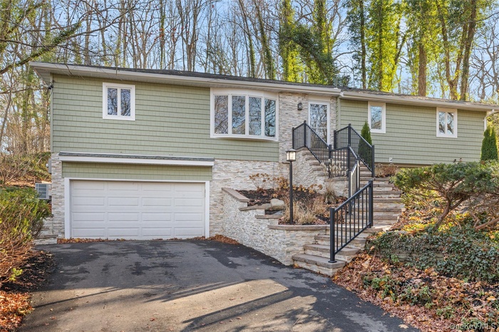 View of front of home with stone siding, driveway, and an attached garage